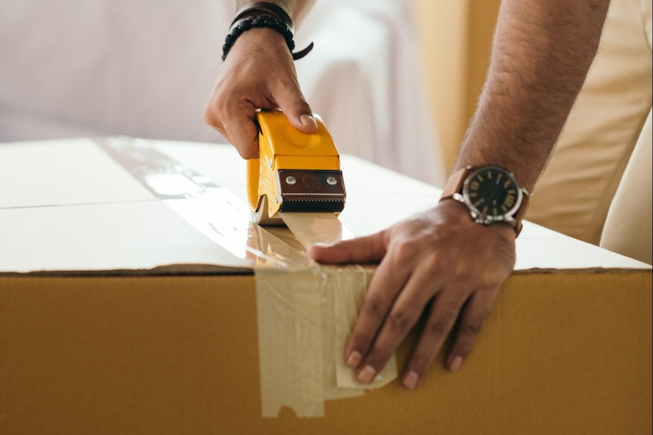 adding packing tape on moving box