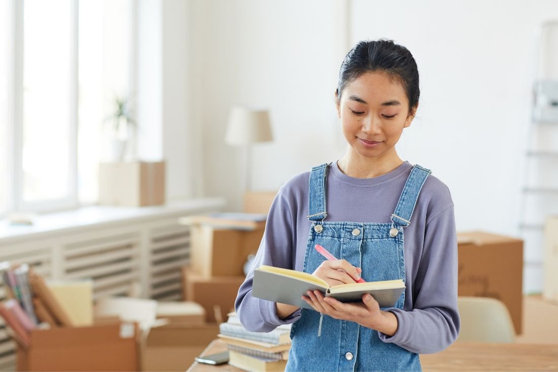 Woman Writing A Detailed Relocation Plan Before Moving Day