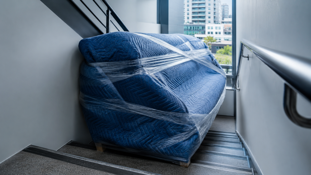 How to move a sofa interstate with Six Brothers Removalists, showing a wrapped sofa on apartment stairs